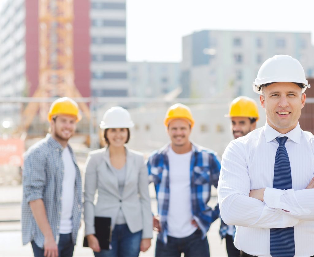 group of smiling builders in hardhats outdoors